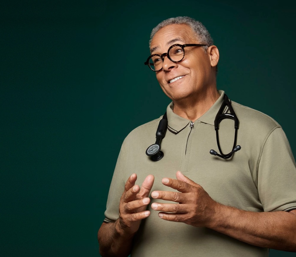 Doctor in a sage polo with a stethoscope, against a deep green backdrop